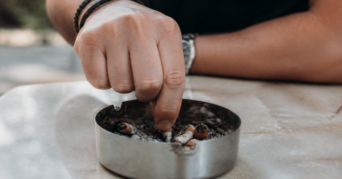 Personne ecrasant cigarette dans cendrier avec determination evidente