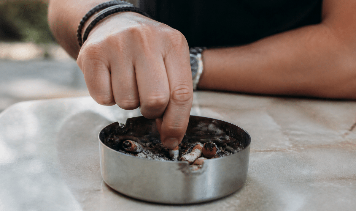 Personne ecrasant cigarette dans cendrier avec determination evidente