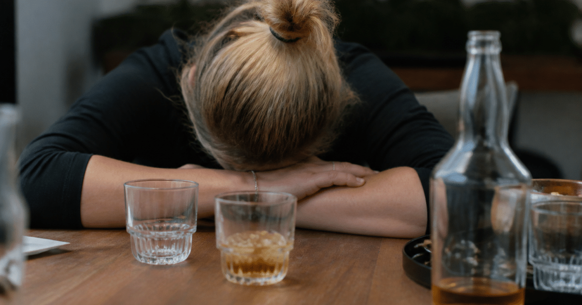 Personne affondree sur table avec verres alcoolises devant elle