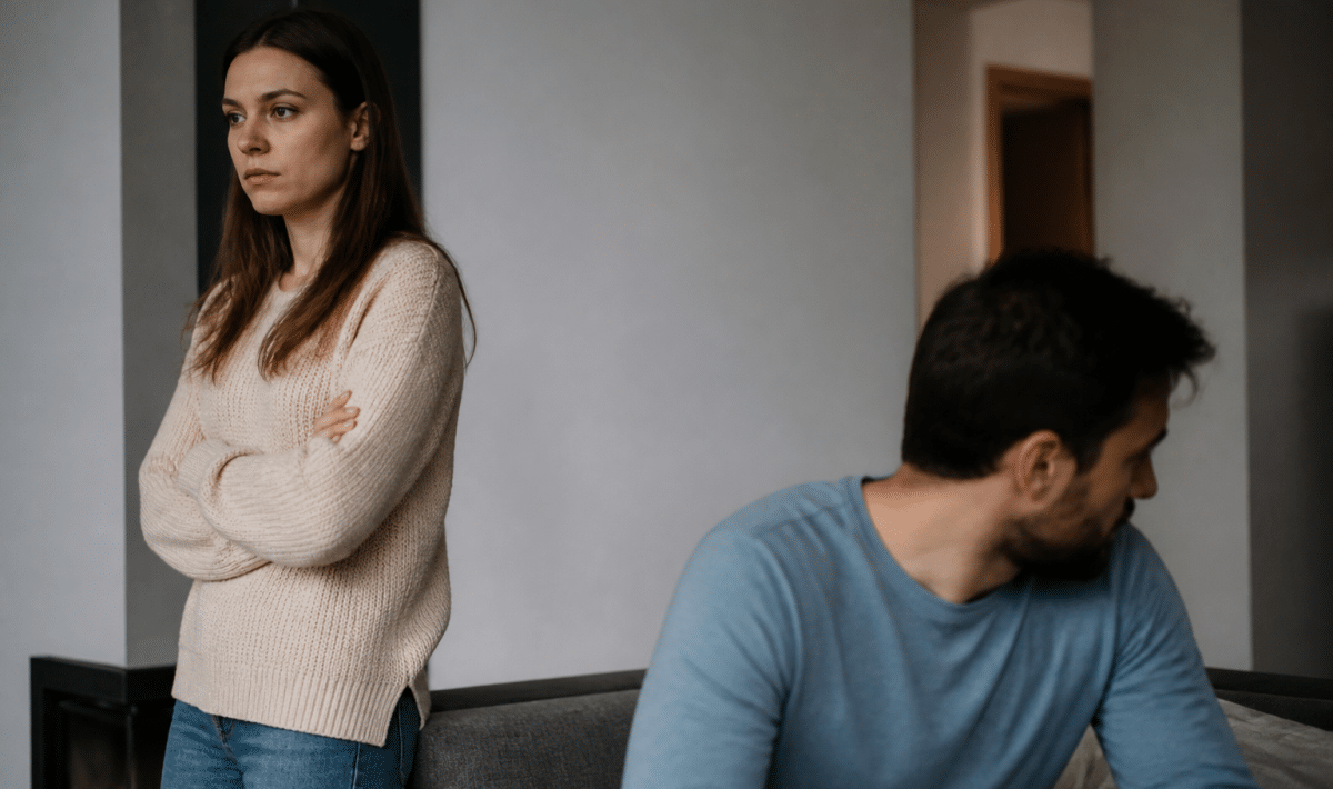 Homme assis tournant le dos a femme debout les bras croises