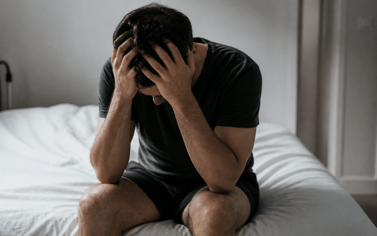 Homme tremblant assis seul sur lit blanc
