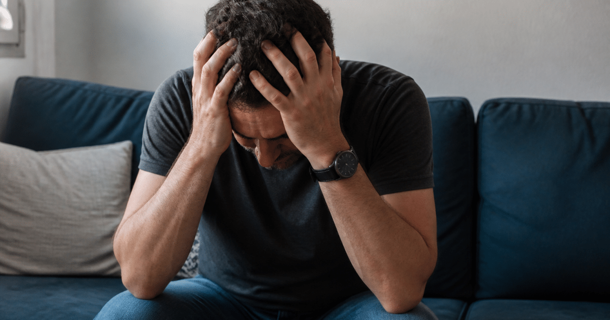 Homme tremblant assis tenant sa tete entre ses mains