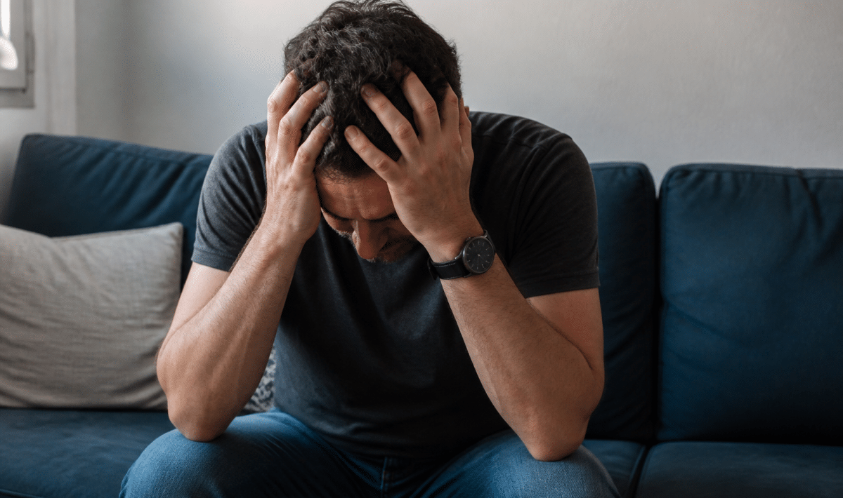 Homme tremblant assis tenant sa tete entre ses mains
