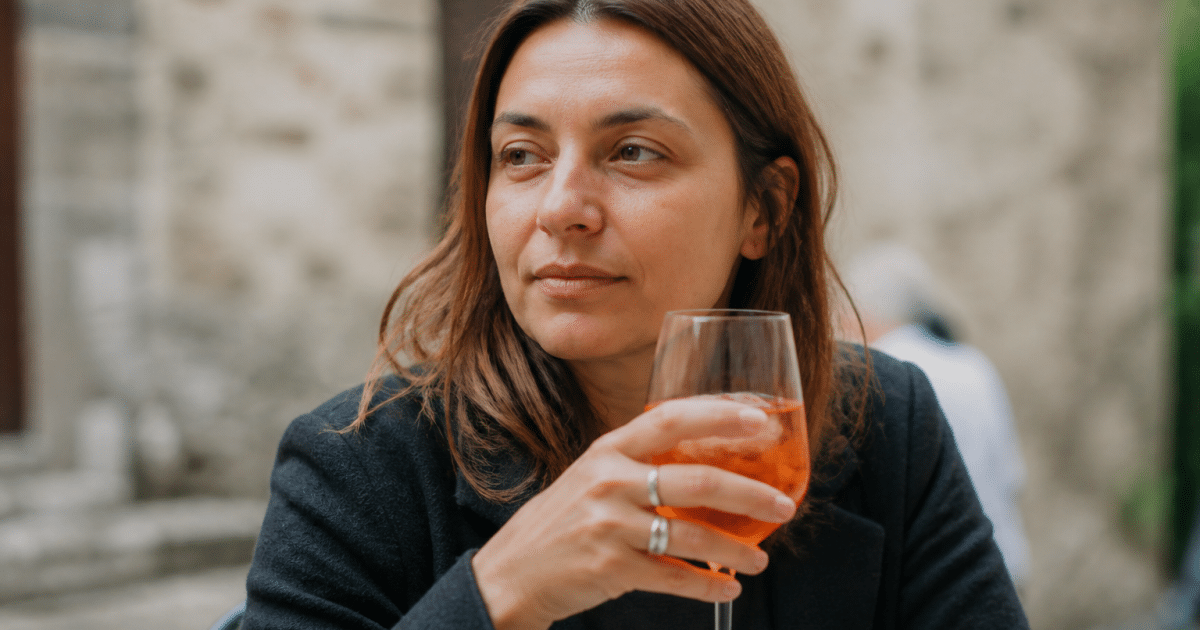 Personne assise tenant verre alcool devant elle