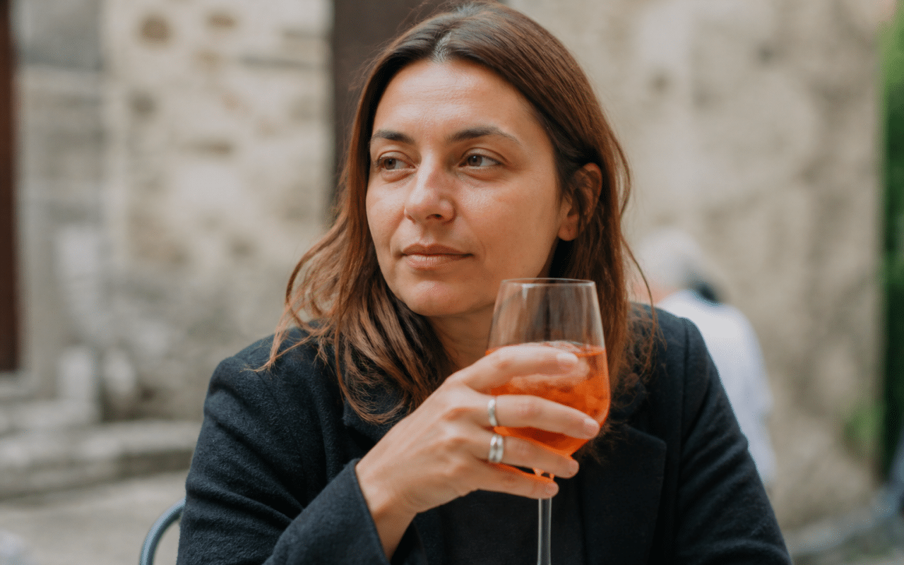 Personne assise tenant verre alcool devant elle