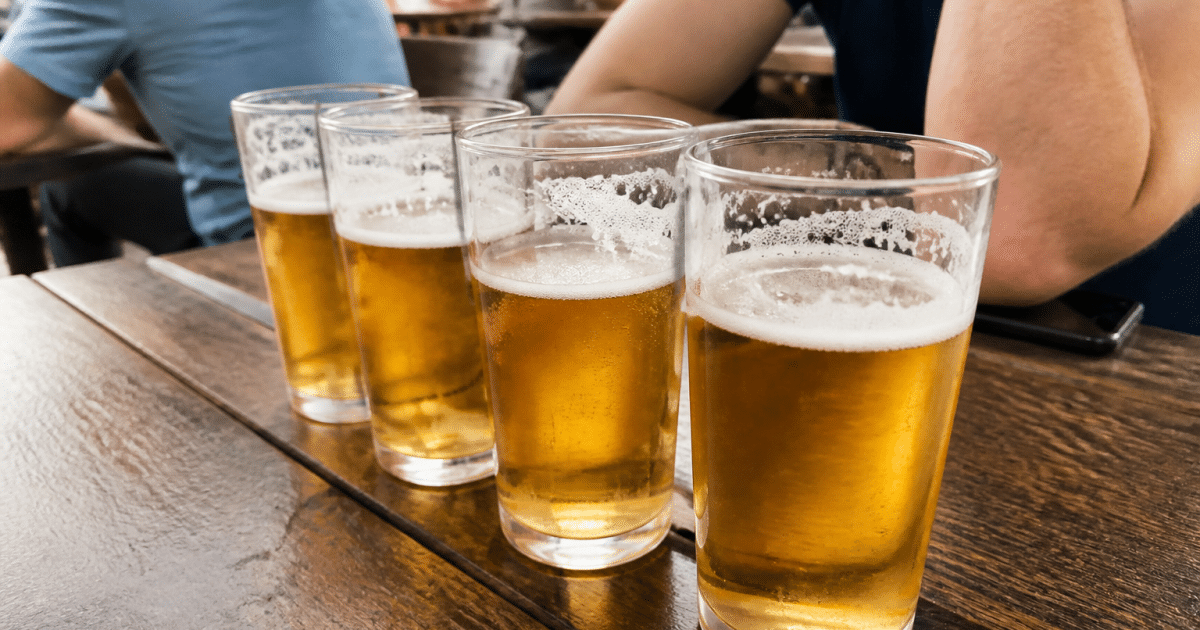 Plusieurs verres de biere alignes sur une table.