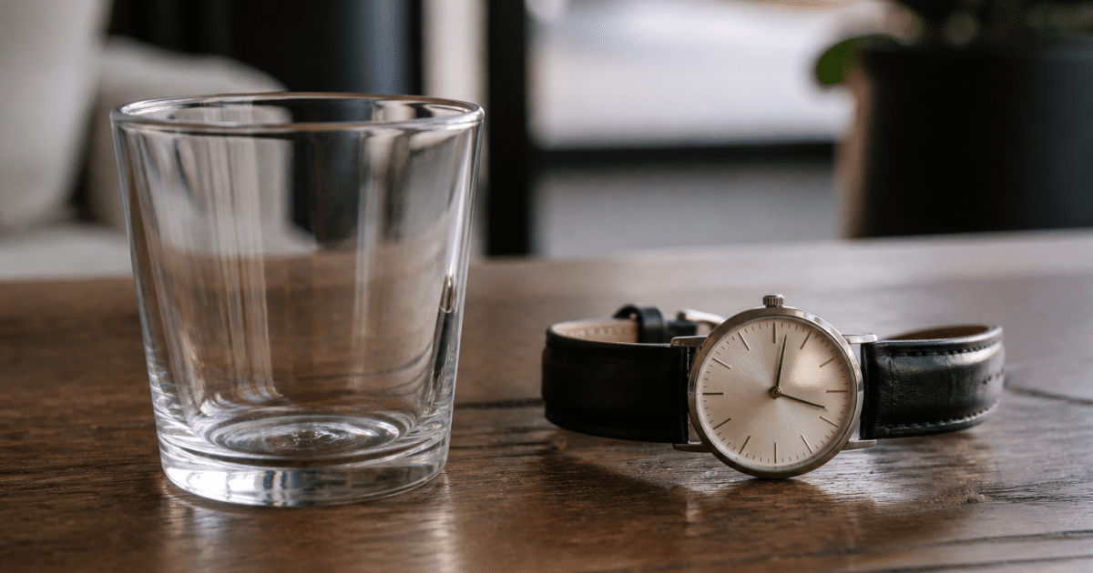 Verre vide posé à cote d'une montre analogique