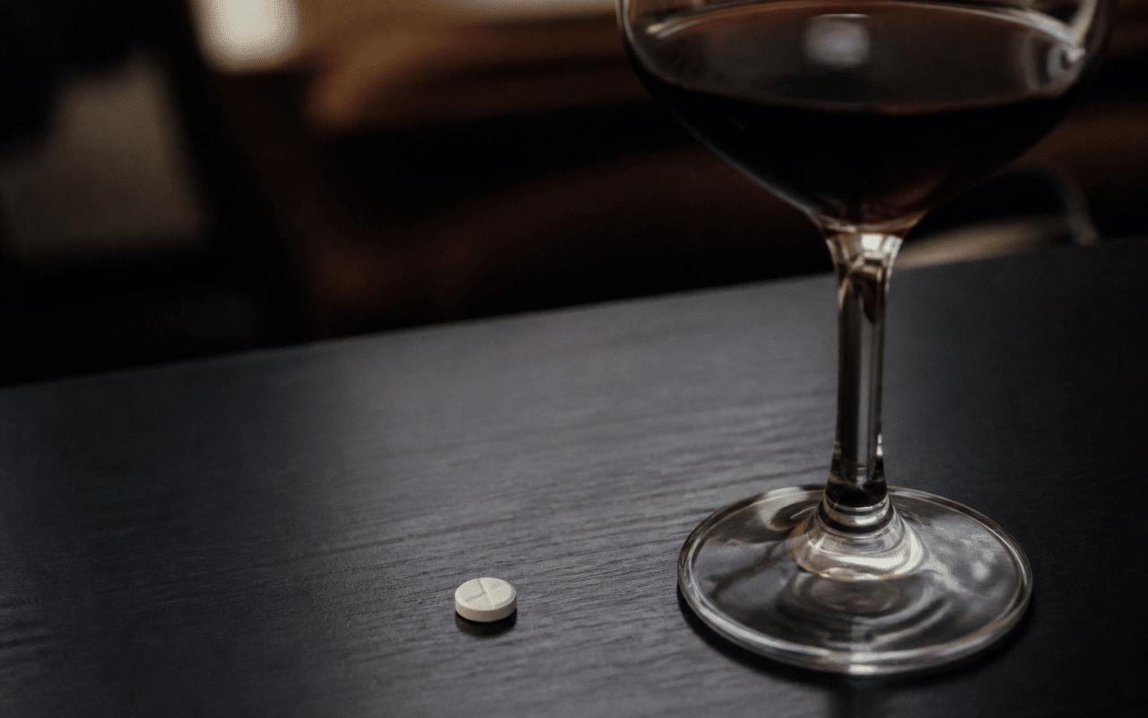 Verre de vin rouge et comprime blanc sur table noire