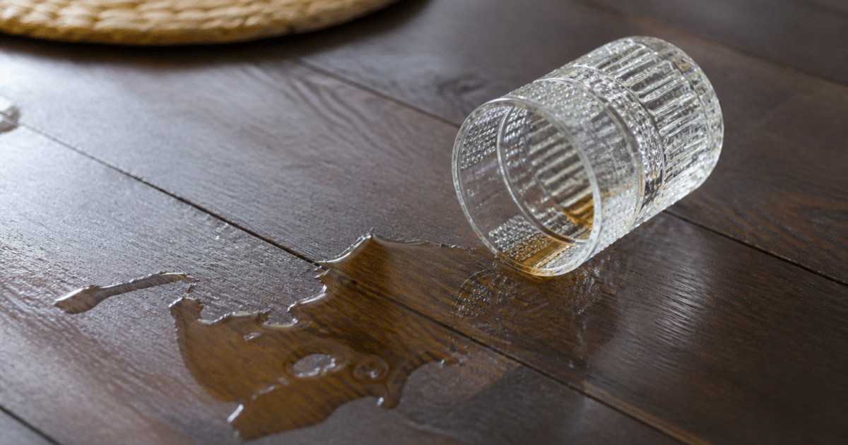Verre de whisky renversé sur table en bois sombre.