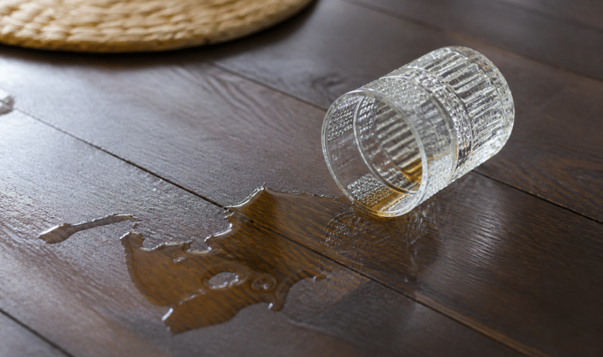 Verre de whisky renversé sur table en bois sombre.