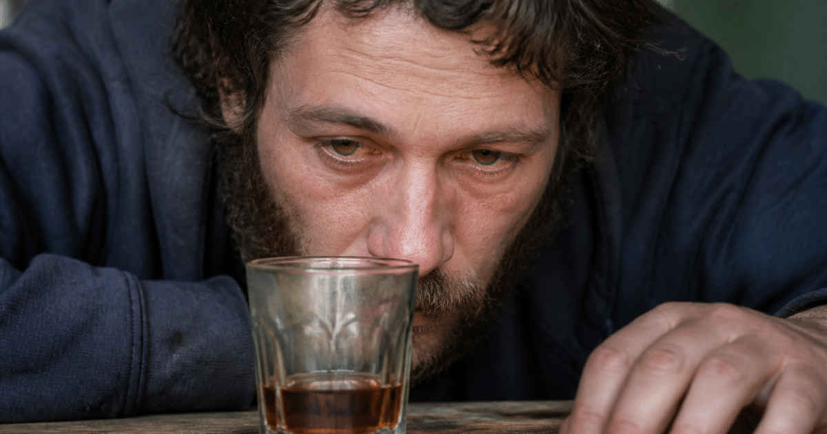 Personne aux yeux jaunes rouges penchee sur verre alcool